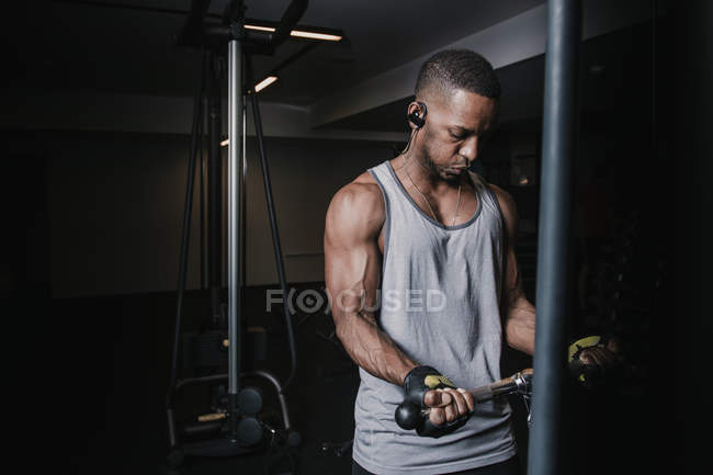 Hombre negro haciendo ejercicio en la máquina - foto de stock