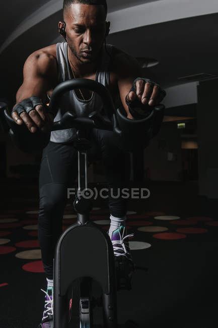 Homme noir sérieux sur vélo d'appartement dans la salle de gym — Photo de stock
