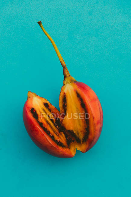 Two halves of delicious cut tamarillo on bright blue background — Stock Photo