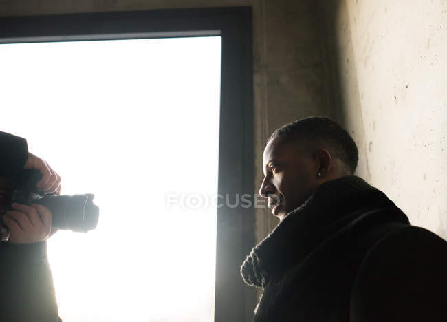 Man with professional photo camera taking pictures of stylish African American man near concrete wall — Stock Photo