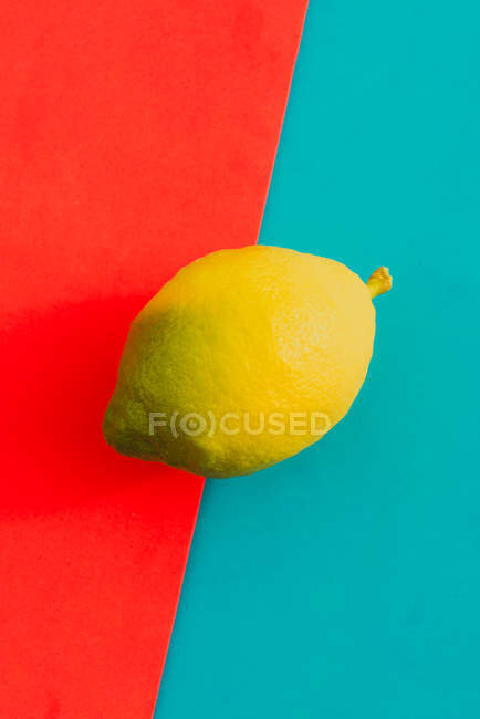 Frische reife Zitrone auf leuchtend rotem und blauem Hintergrund — Stockfoto