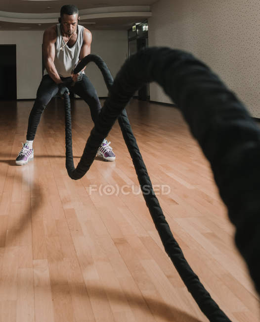 Black guy exercising with ropes in gym — Stock Photo