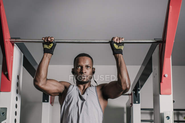 Black guy hanging on bar in gym — Stock Photo