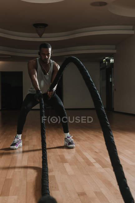 Preto cara exercício com cordas no ginásio — Fotografia de Stock