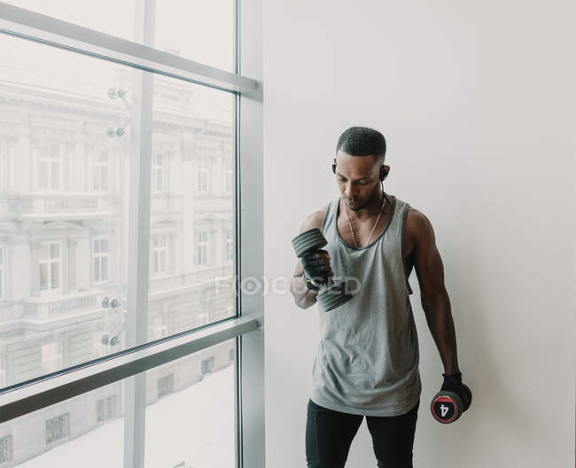 Чорний чоловік з гантелями в спортзалі — стокове фото