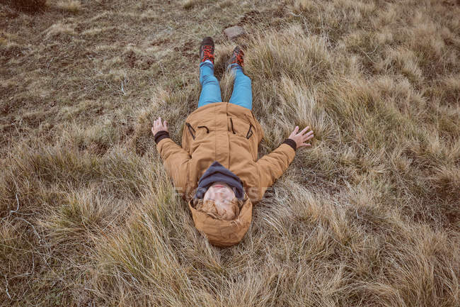 Criança deitada na grama seca perto do riacho — Fotografia de Stock