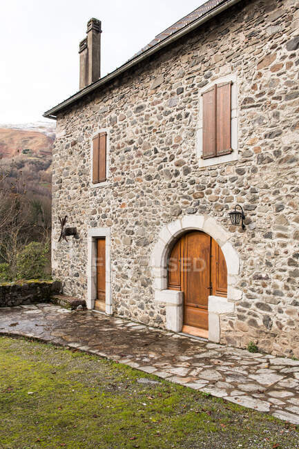 Yard with green grass between grey rock old house with red doors in Pyrenees — Stock Photo