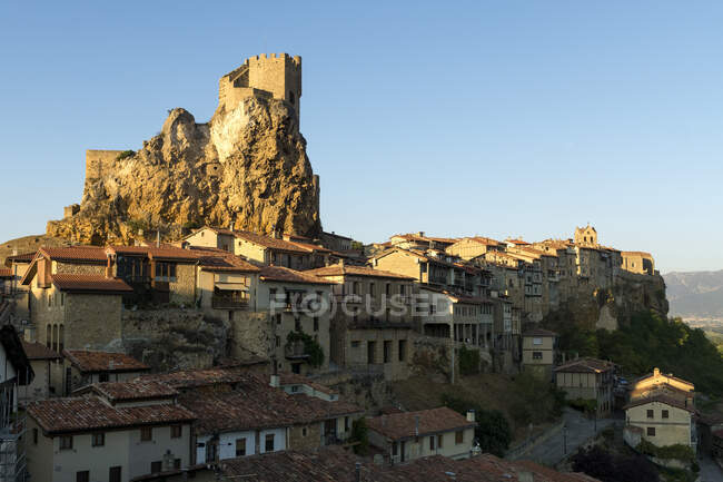 Cidade velha medieval colocada na montanha rochosa com fortaleza no topo em luz solar brilhante contra o céu azul — Fotografia de Stock