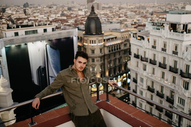 Handsome man on roof near old buildings and huge banner — Stock Photo