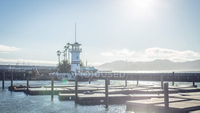 Faro sulla riva vicino alla superficie dell'acqua e cielo blu con sole a San Francisco, Stati Uniti — Foto stock