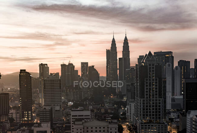 Picturesque view city with modern skyscrapers and beautiful pink sky at sunset in Malaysia — Stock Photo