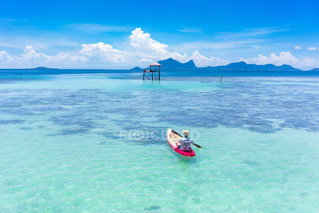Voltar visão masculina de barco na canoa com remo no mar azul incrível e céu azul na Malásia — Fotografia de Stock
