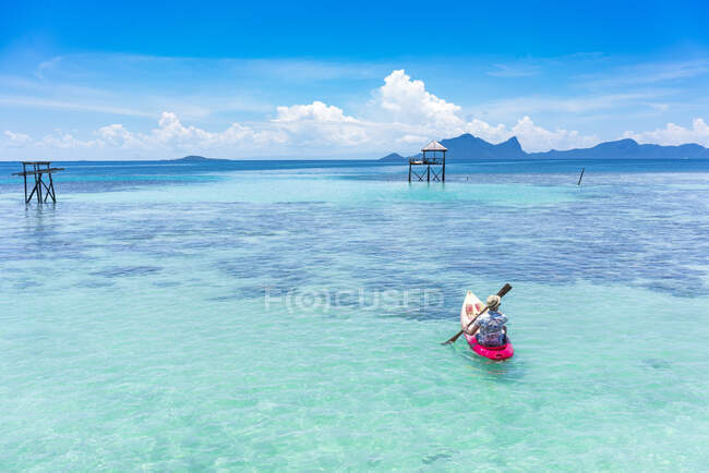 У Малайзії самець катається на каное з веслом на дивовижному блакитному морі і синьому небі. — стокове фото