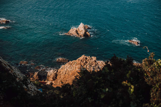 Costa rochosa e calma água do mar azul — Fotografia de Stock
