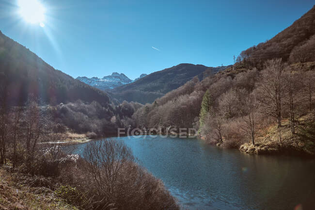 Vista pitoresca do lago perto da floresta seca, belas montanhas e céu azul em dia ensolarado em Canfranc-Station, Huesca, Espanha — Fotografia de Stock