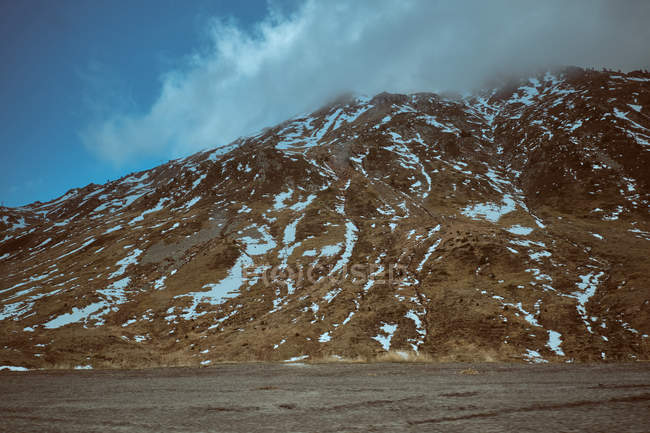 Nuage sur la montagne rocheuse couverte de neige — Photo de stock
