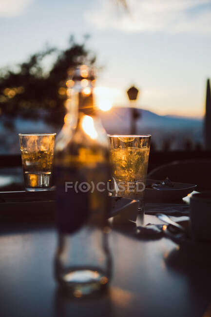 Два бокала с холодным напитком, стоящие на столе ресторана на открытом воздухе на размытом фоне города во время заката в Испании — стоковое фото