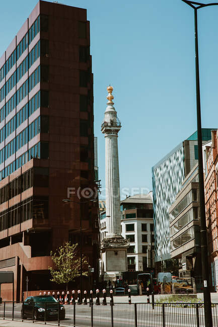 LONDRES, REINO UNIDO - 23 DE OCTUBRE DE 2018: Impresionante vista del impresionante monumento de la columna que se encuentra cerca de edificios modernos en el día soleado en la calle de Londres, Inglaterra - foto de stock