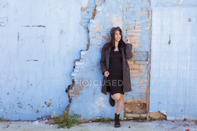 Стильна латиноамериканського молодої жінки, спираючись на пошарпаний цегляну стіну — стокове фото