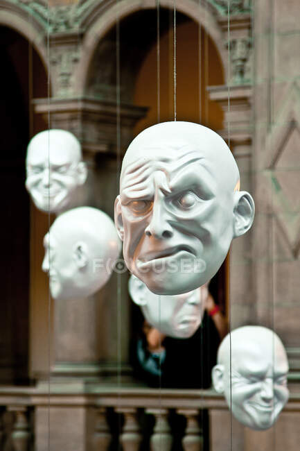 Artificial heads with various grimaces hanging inside beautiful building — Stock Photo