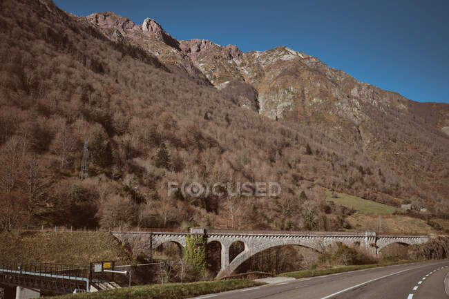 Wonderful view of bridge near asphalt route and dry forest growing on mountain in Canfranc-Station, Huesca, Spain — Stock Photo