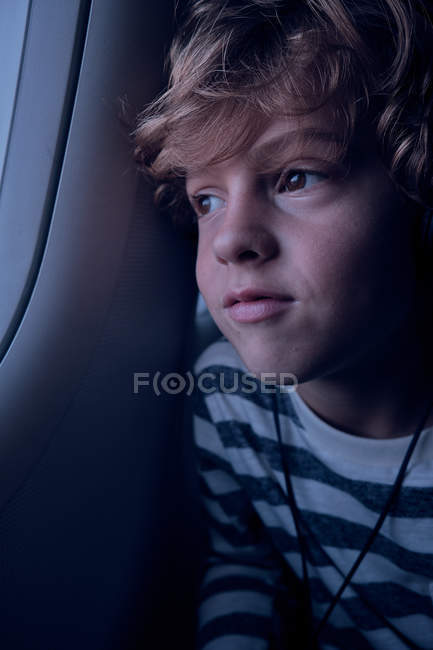 Garçon mignon avec écouteurs dans l'avion — Photo de stock