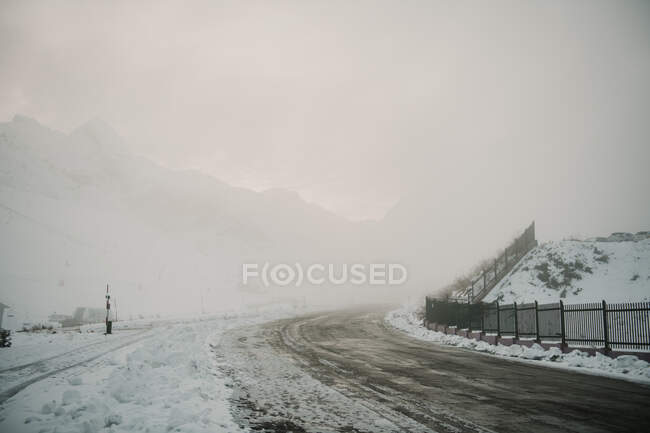 Snowy route running between mountains in fog in Pyrenees — Stock Photo