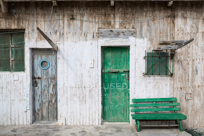 Pequeno banco verde perto da fachada intempérie da casa de madeira — Fotografia de Stock