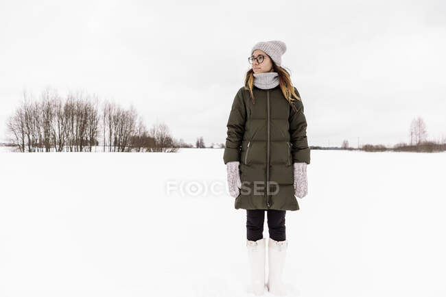 Молода жінка взимку одягається на сніговому полі. — стокове фото