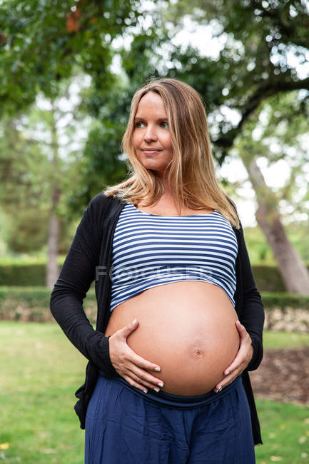 Souriant femme enceinte attrayant dans le parc — Photo de stock