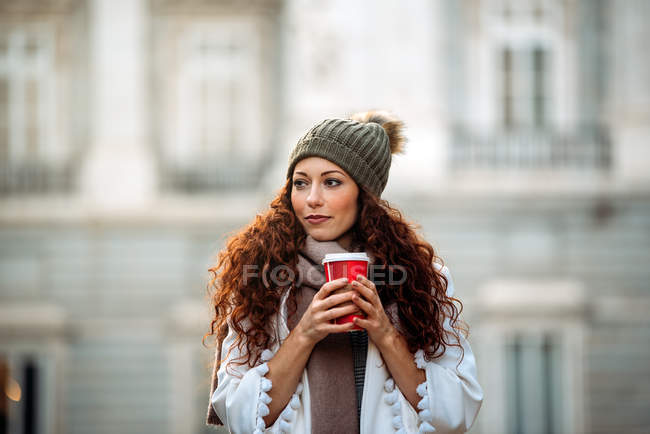 Giovane donna che beve caffè vagando per le strade di Madrid in inverno — Foto stock