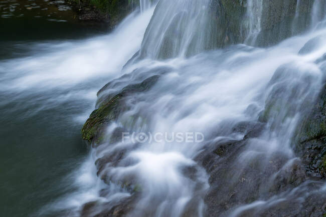 Caída de agua que fluye sobre rocas musgosas - foto de stock