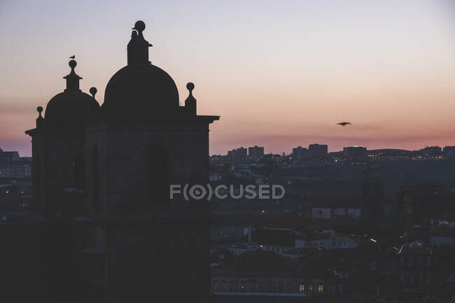 Вид силуэта собора в сумерках на инфраструктуру большого города на фоне сумеречного неба — стоковое фото