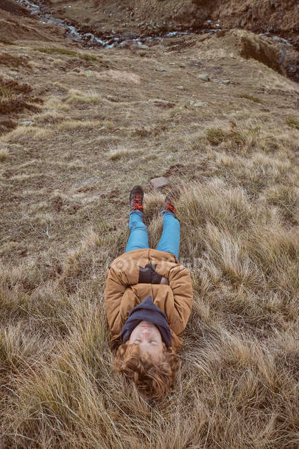 Kind liegt auf trockenem Gras in Bachnähe — Stockfoto