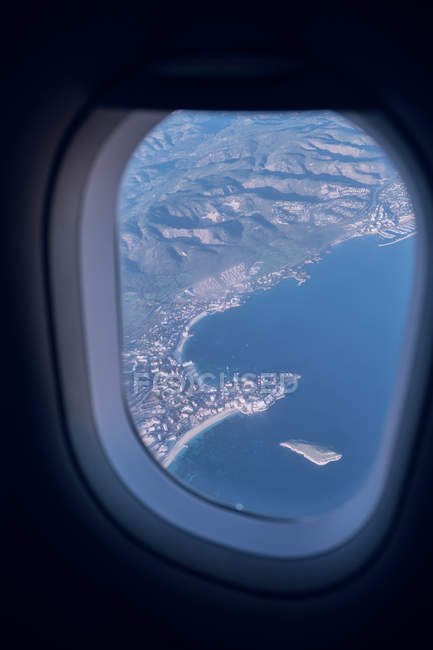 Blick über Land mit Bergen und Meer aus dem Flugzeugfenster — Stockfoto
