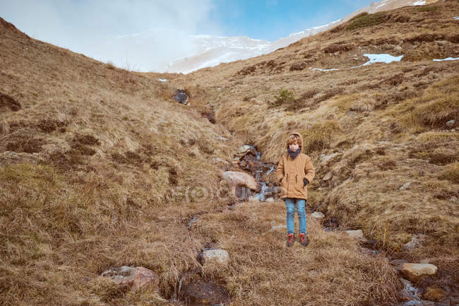 Netter Junge steht auf einem Hügel in Bachnähe — Stockfoto