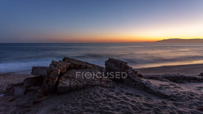 Удивительное скалистое побережье спокойного моря во время великолепного заката — стоковое фото