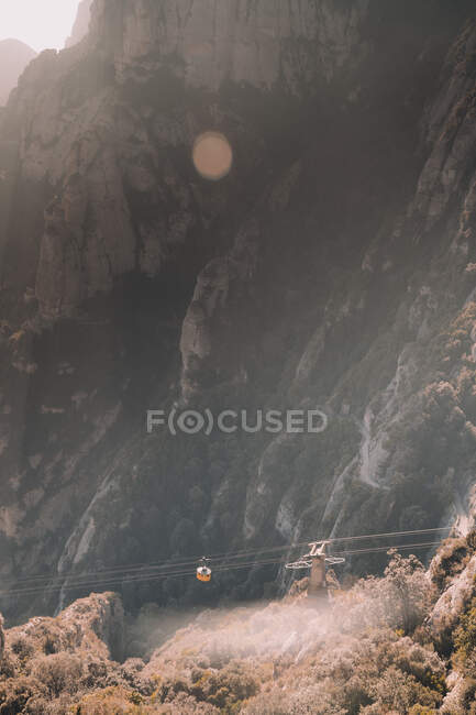 Из верхней кабины канатной дороги, проходящей между каменными горами в солнечную погоду — стоковое фото