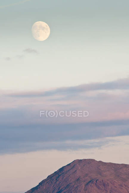 Bella vista della bella luna e nuvole spesse sul cielo serale sopra la vetta della montagna — Foto stock