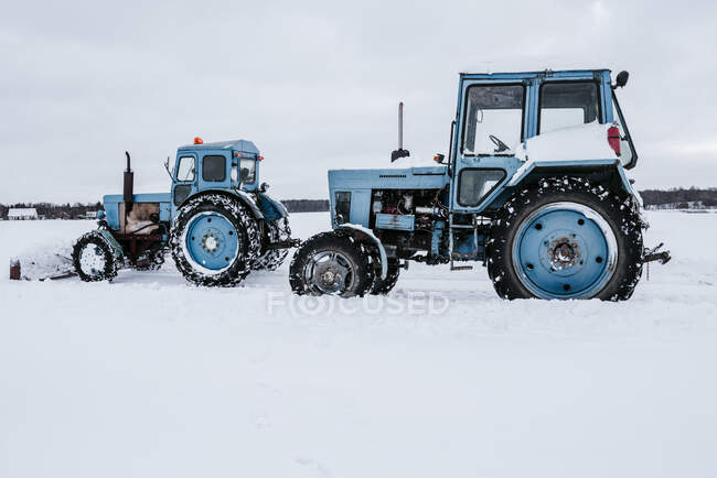 Вид сбоку тракторов, убирающих снег с луга в сельской местности, Литва — стоковое фото