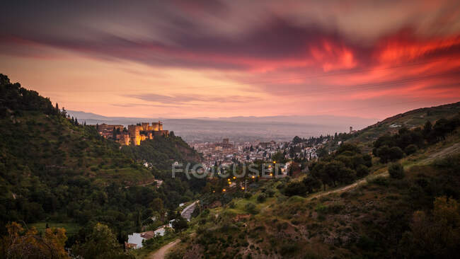Malerischer Blick auf den schönen Abendhimmel mit dicken Wolken über grünen Hügeln und der Stadt — Stockfoto