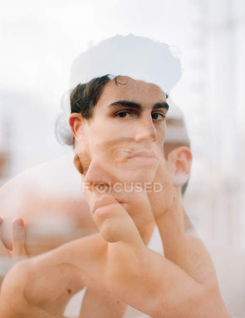 Двойное обнажение брюнетки без рубашки молодого парня, смотрящего в камеру на размытом фоне — стоковое фото