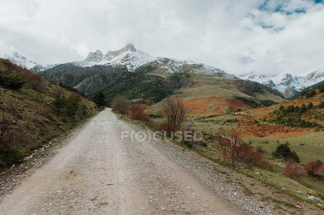 Ruta de campo en valle con bosques y montañas maravillosas en la nieve en los Pirineos - foto de stock