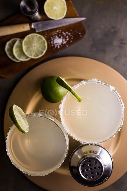 Коктейль Маргарита в стаканах на тарелке с ингредиентами — стоковое фото