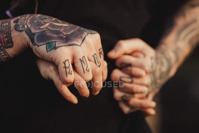 Cropped image of man in tattoos with ring and watch holding hands of woman — Stock Photo