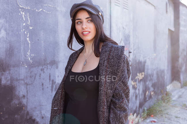 Stylish Hispanic lady standing on street near shabby wall — Stock Photo