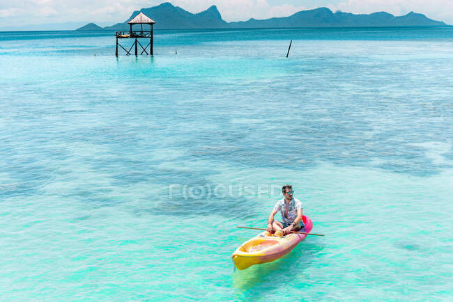 Barco masculino na canoa com remo no incrível mar azul e céu azul na Malásia — Fotografia de Stock