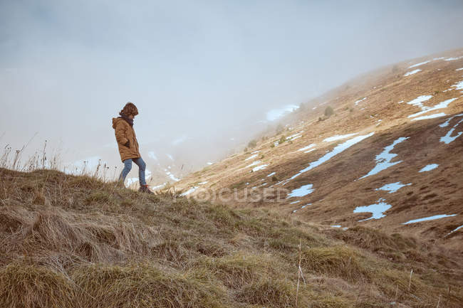 Niño anónimo de pie en la cima de la colina - foto de stock