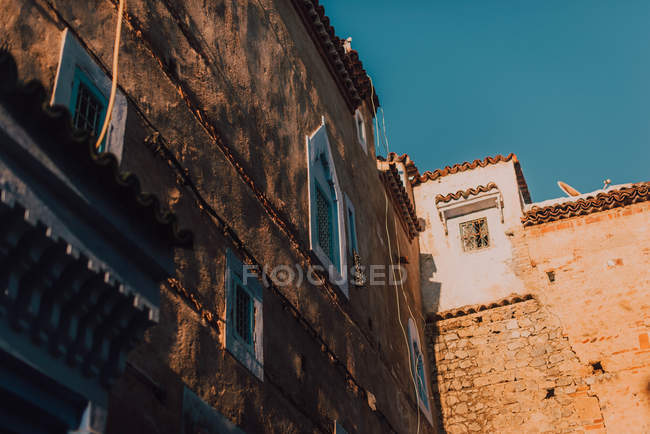 Fachada del viejo edificio de mala calidad a la luz del sol, Chefchaouen, Marruecos - foto de stock