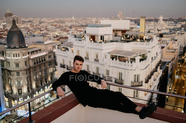 Schöner Mann auf Dach neben alten Gebäuden und riesigem Banner — Stockfoto